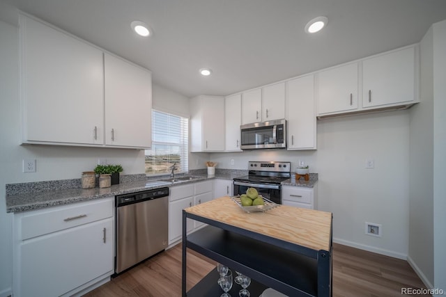 kitchen featuring a sink, stainless steel appliances, recessed lighting, and white cabinetry