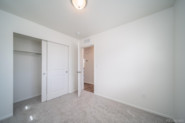 unfurnished bedroom featuring visible vents, baseboards, carpet, and a closet