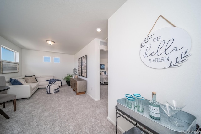 carpeted living area featuring baseboards and visible vents