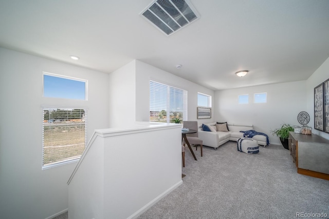 living area featuring visible vents, light carpet, and baseboards