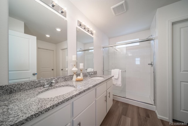 full bathroom featuring visible vents, a shower stall, wood finished floors, and a sink