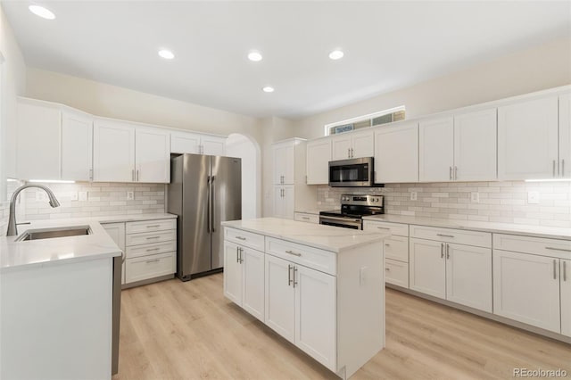 kitchen with appliances with stainless steel finishes, white cabinetry, a kitchen island, and sink