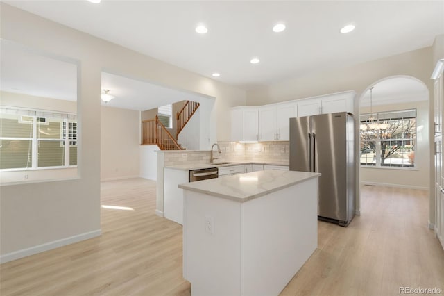 kitchen featuring white cabinets, a kitchen island, appliances with stainless steel finishes, and light hardwood / wood-style flooring