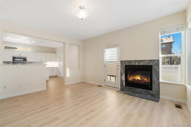 unfurnished living room featuring a premium fireplace and light hardwood / wood-style flooring