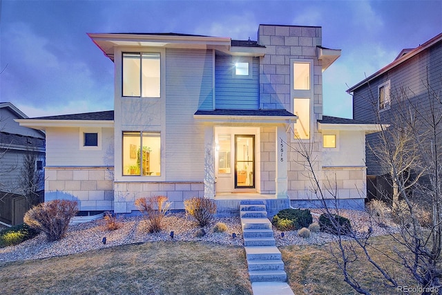 view of front of house featuring stone siding and a shingled roof