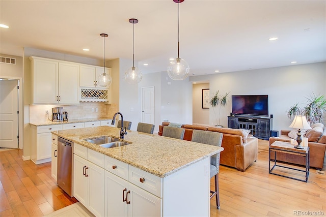 kitchen with visible vents, a breakfast bar, a sink, light wood-style floors, and stainless steel dishwasher