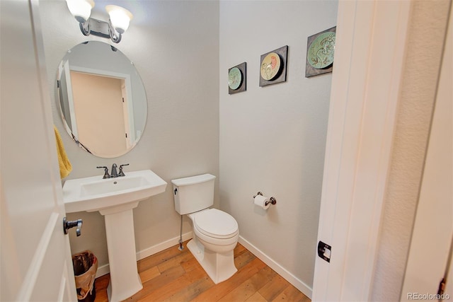 bathroom with toilet, a sink, baseboards, and wood finished floors