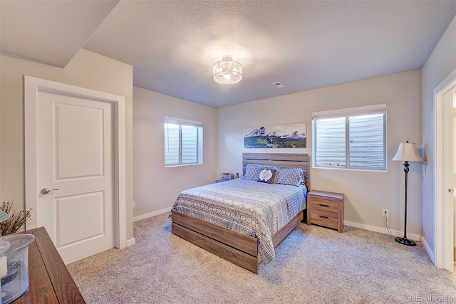 carpeted bedroom with visible vents, a textured ceiling, and baseboards