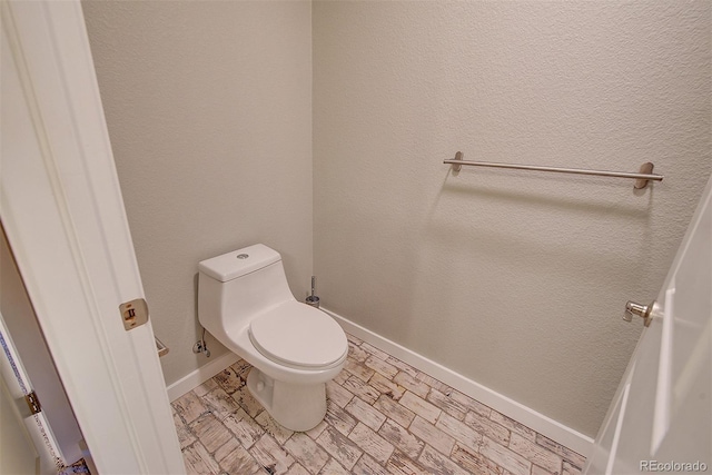 bathroom featuring toilet and baseboards