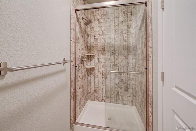 full bathroom featuring a textured wall and a shower stall