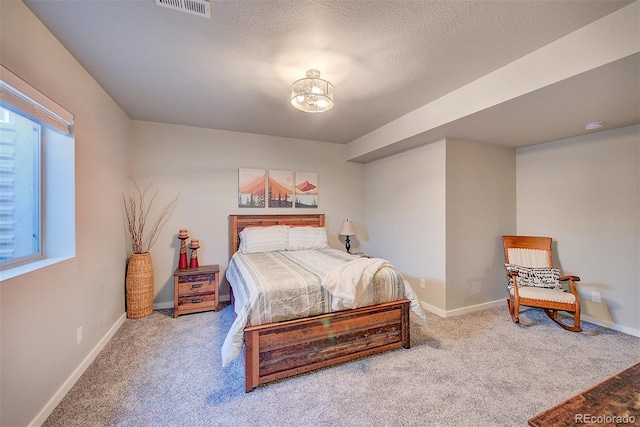 carpeted bedroom featuring a textured ceiling, visible vents, and baseboards