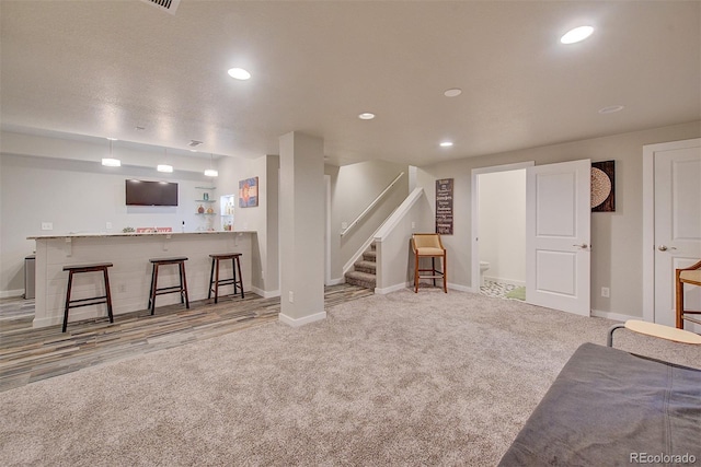 living area featuring carpet floors, wet bar, recessed lighting, and stairs