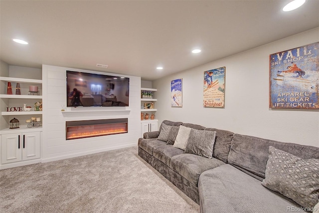 carpeted living room with a glass covered fireplace and recessed lighting