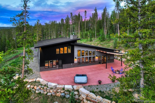 133 Adams Way, Breckenridge, CO 80424 - back of house at dusk with a chimney, a patio area, and a view of trees