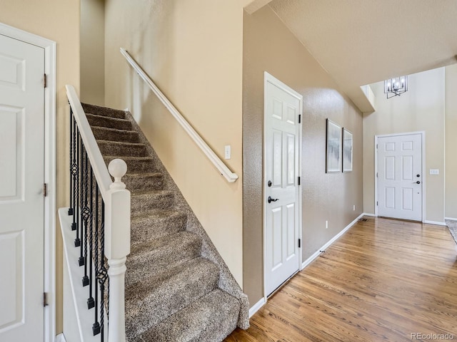 foyer featuring stairway, light wood-style floors, baseboards, and a chandelier