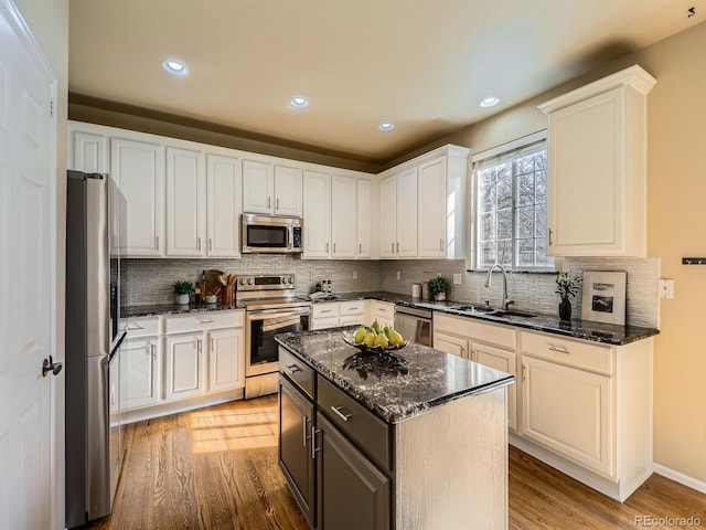 kitchen featuring decorative backsplash, light wood-style flooring, stainless steel appliances, white cabinetry, and a sink