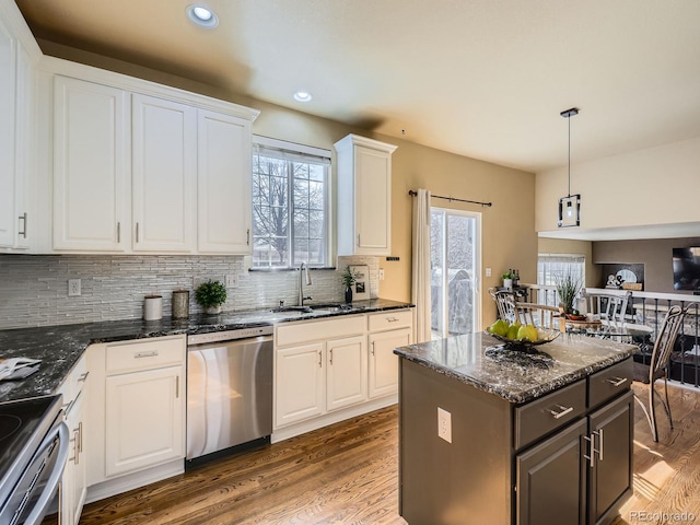 kitchen featuring white cabinets, appliances with stainless steel finishes, wood finished floors, and a sink