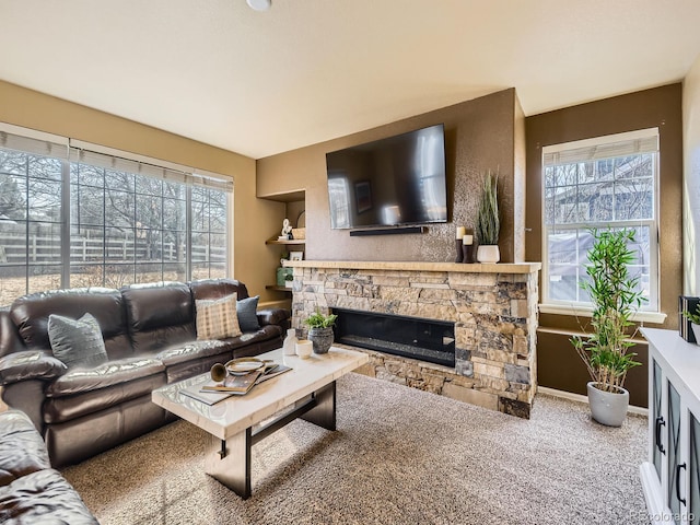 living area featuring baseboards, carpet floors, and a stone fireplace