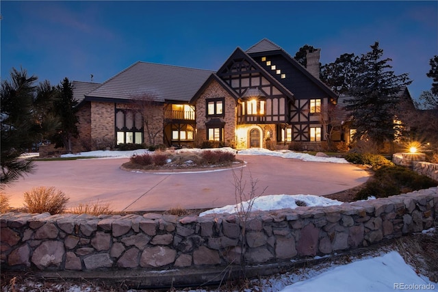 tudor home with curved driveway and a chimney