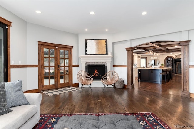 living room with recessed lighting, coffered ceiling, wood finished floors, a lit fireplace, and decorative columns