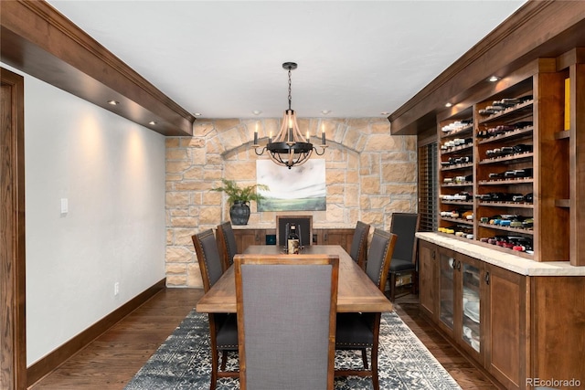 wine area with dark wood-style floors, baseboards, and an inviting chandelier