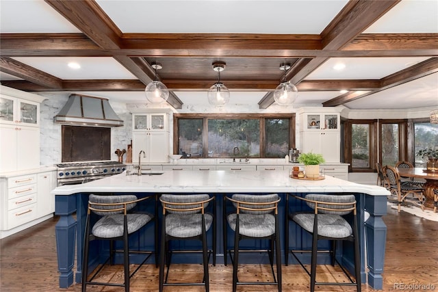 kitchen with custom exhaust hood, coffered ceiling, and a sink