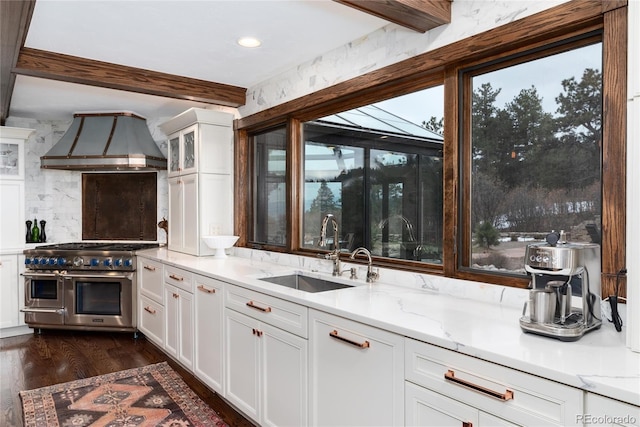 kitchen featuring range with two ovens, dark wood-type flooring, a sink, white cabinets, and custom range hood