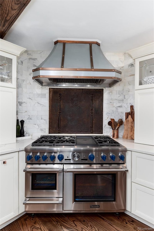 kitchen featuring tasteful backsplash, custom exhaust hood, white cabinetry, and double oven range