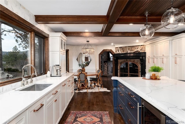 kitchen featuring beam ceiling, blue cabinetry, dark wood-type flooring, white cabinets, and a sink