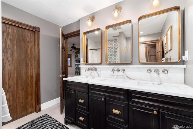 full bathroom with baseboards, double vanity, a sink, and tile patterned floors