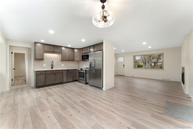6448 Ingalls Ct, Arvada, CO 80003 - kitchen with light wood finished floors, stainless steel appliances, tasteful backsplash, and light countertops