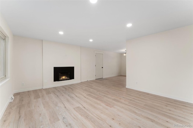 6448 Ingalls Ct, Arvada, CO 80003 - unfurnished living room featuring baseboards, a warm lit fireplace, light wood-style flooring, and recessed lighting