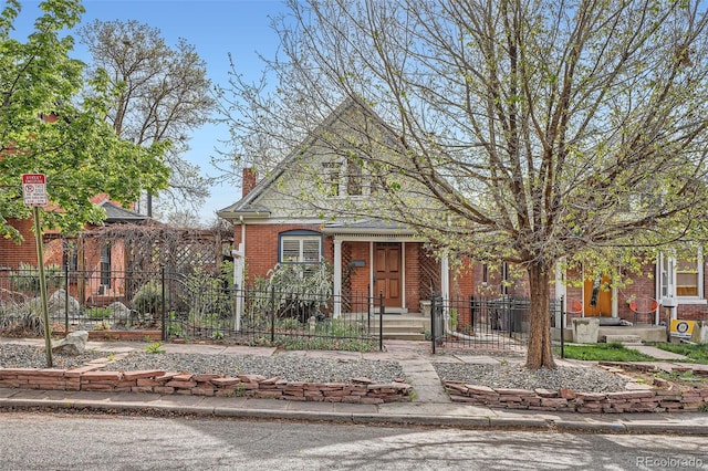 bungalow with brick siding, a fenced front yard, and a chimney