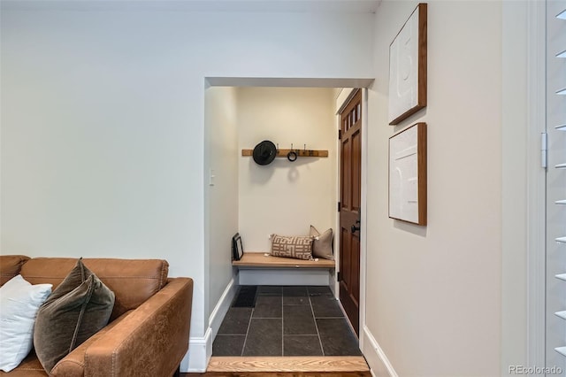 hall featuring baseboards and dark tile patterned floors