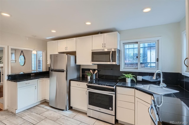 kitchen featuring white cabinets, stainless steel appliances, a wealth of natural light, and a sink