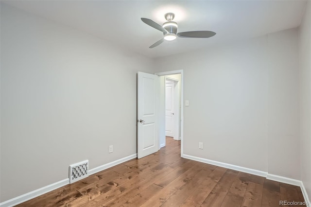 spare room with wood-type flooring, ceiling fan, visible vents, and baseboards