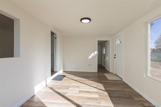 corridor featuring wood finished floors, a wealth of natural light, and baseboards