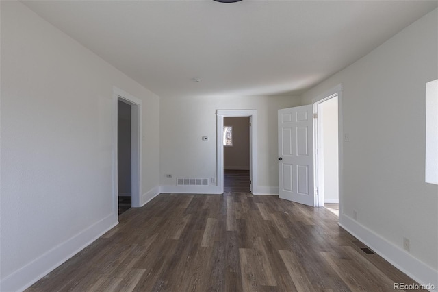 spare room with baseboards, visible vents, and dark wood finished floors