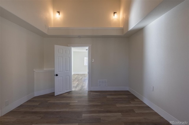 empty room with wood finished floors, visible vents, and baseboards