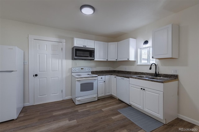 kitchen featuring dark countertops, white appliances, white cabinetry, and a sink