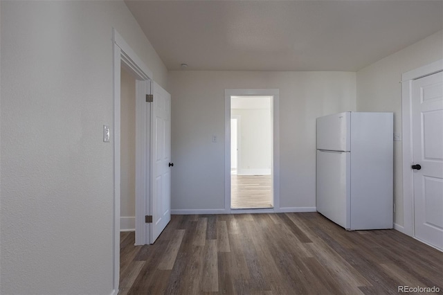 interior space with baseboards, wood finished floors, and freestanding refrigerator