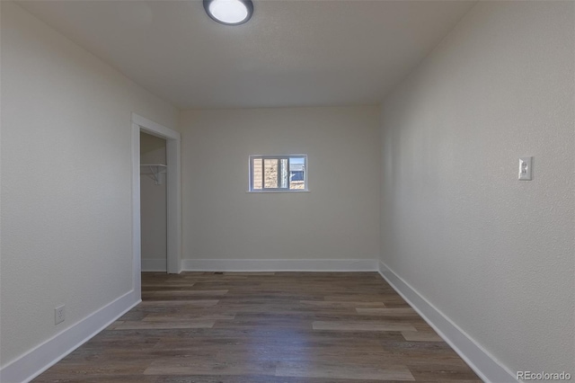 spare room featuring baseboards and dark wood-type flooring