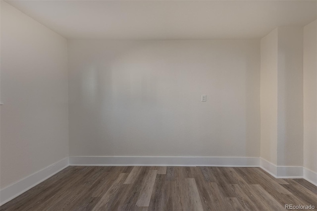 empty room featuring dark wood-style flooring and baseboards