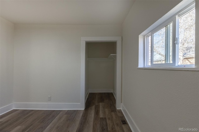 corridor featuring baseboards and dark wood-type flooring