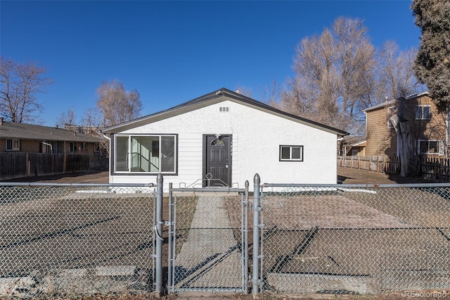 rear view of property with a gate, fence, and stucco siding