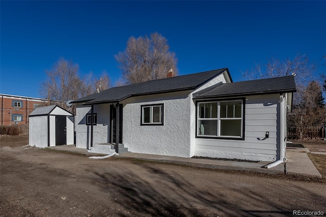 ranch-style house featuring stucco siding, a chimney, a storage unit, and an outdoor structure