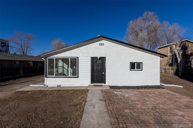 view of front of house with a patio, fence, and stucco siding