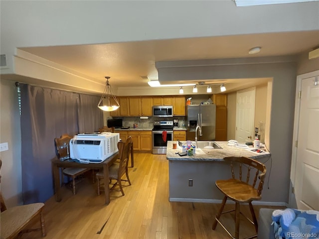 21300 E 42nd Ave, Denver, CO 80249 - kitchen featuring stainless steel appliances, light wood finished floors, a peninsula, a kitchen bar, and brown cabinets