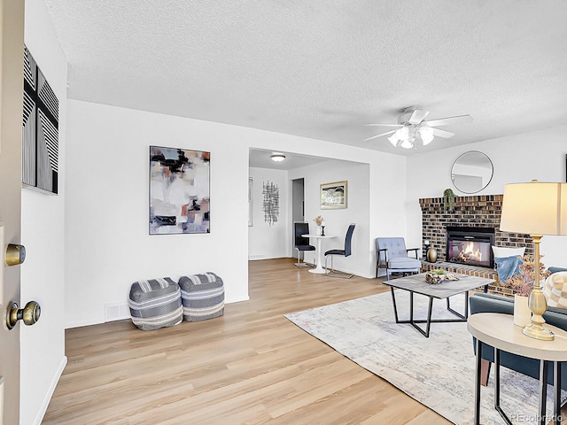5225 Beech St, Arvada, CO 80002 - living room featuring wood finished floors, ceiling fan, a textured ceiling, a fireplace, and baseboards