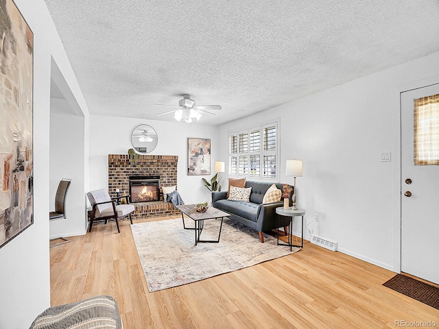 5225 Beech St, Arvada, CO 80002 - living area with ceiling fan, light wood-type flooring, a brick fireplace, a textured ceiling, and baseboards